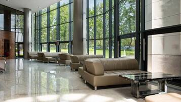 A spacious lobby with large windows, leather sofas, and a glass coffee table.