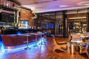 A modern bar area with a counter, bar stools, and a laptop on a table.