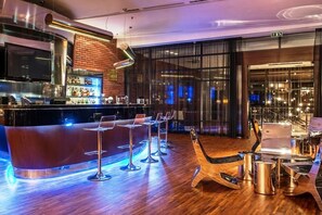 A modern bar area with a counter, bar stools, and a laptop on a table.