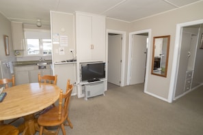 Ett kompakt bostadsutrymme med en matplats, ett litet kök och en TV.