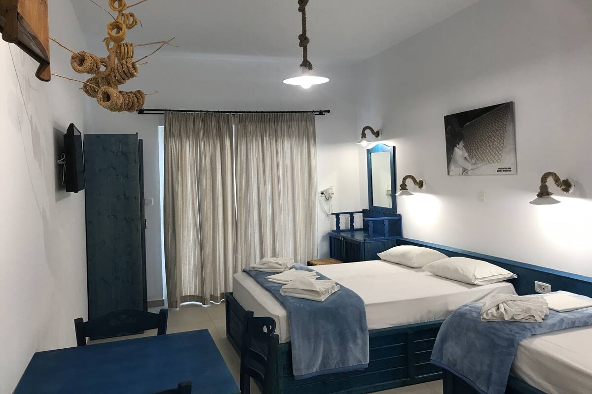 A hotel room with two beds, a desk, a chair, a mirror, and a hanging light fixture.