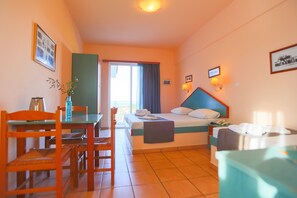 A hotel room with a bed, a desk, a chair, a table, and a window. - Filoxenia Hotel Apartments (Rhodes)