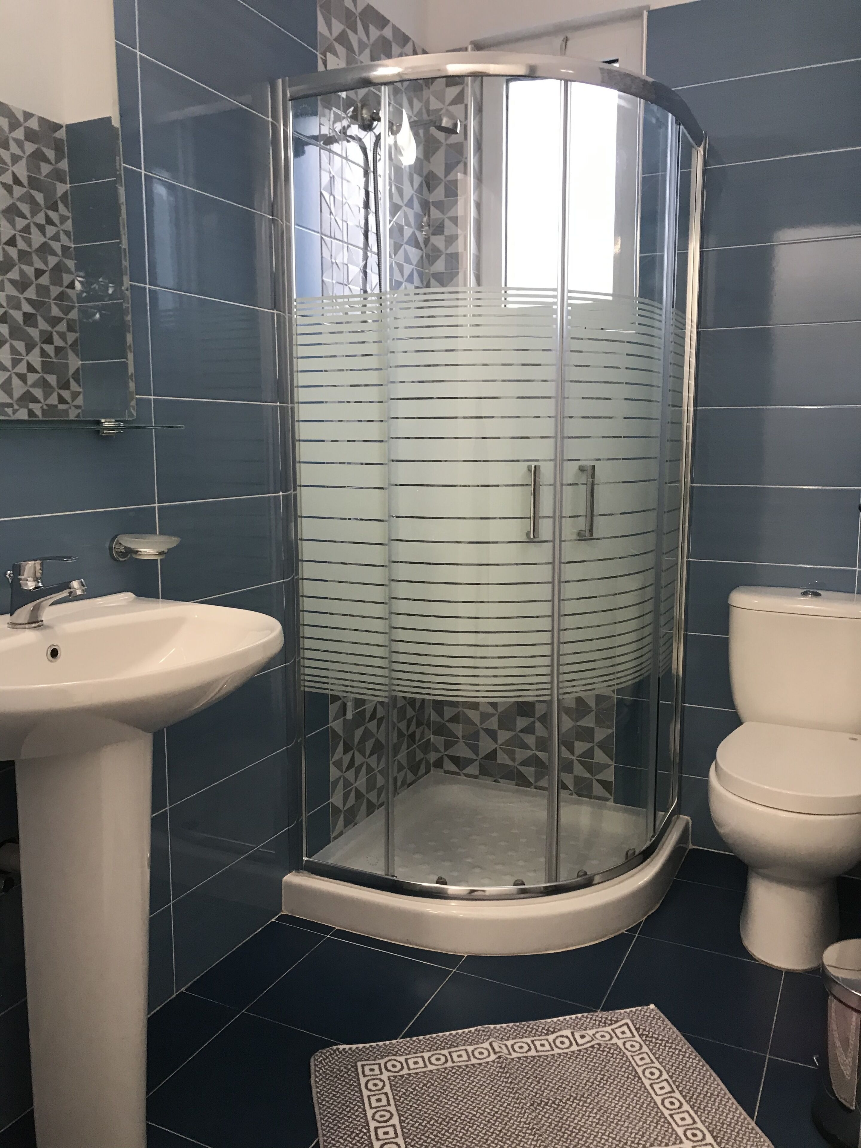 A bathroom with a glass shower enclosure, a sink, and a toilet.