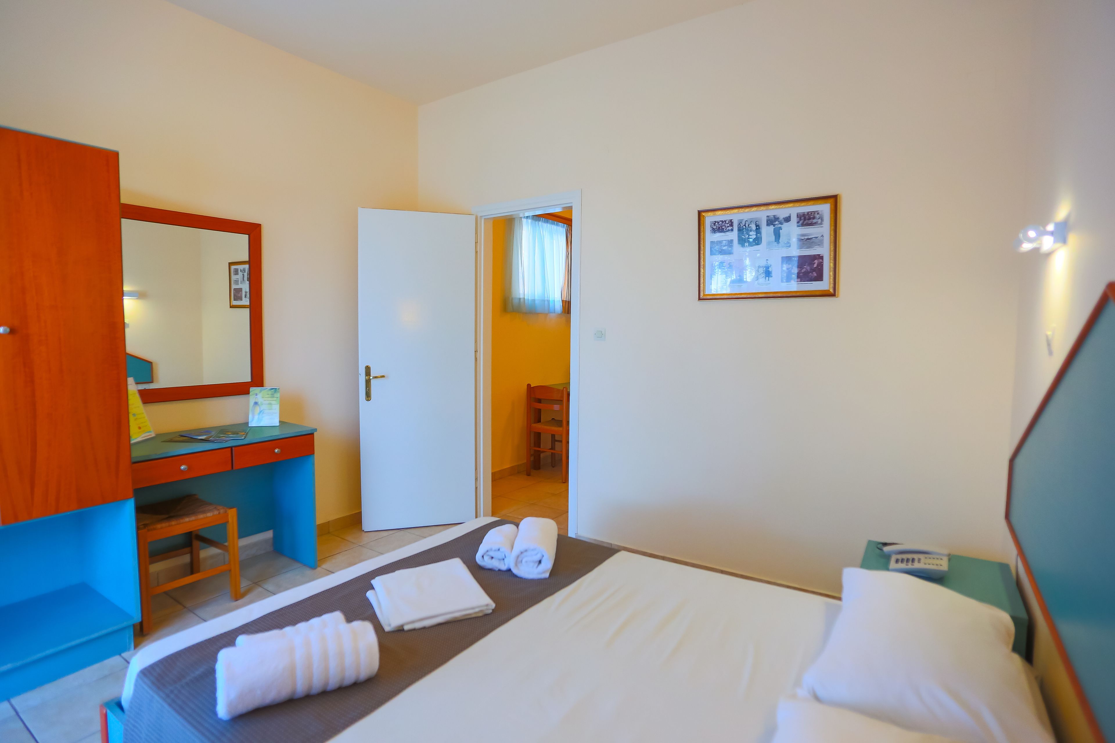 Quarto de hotel com cama, escrivaninha, cadeira e guarda-roupa.