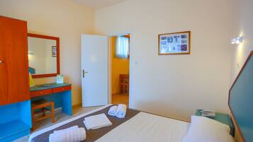 Quarto de hotel com cama, escrivaninha, cadeira e guarda-roupa.