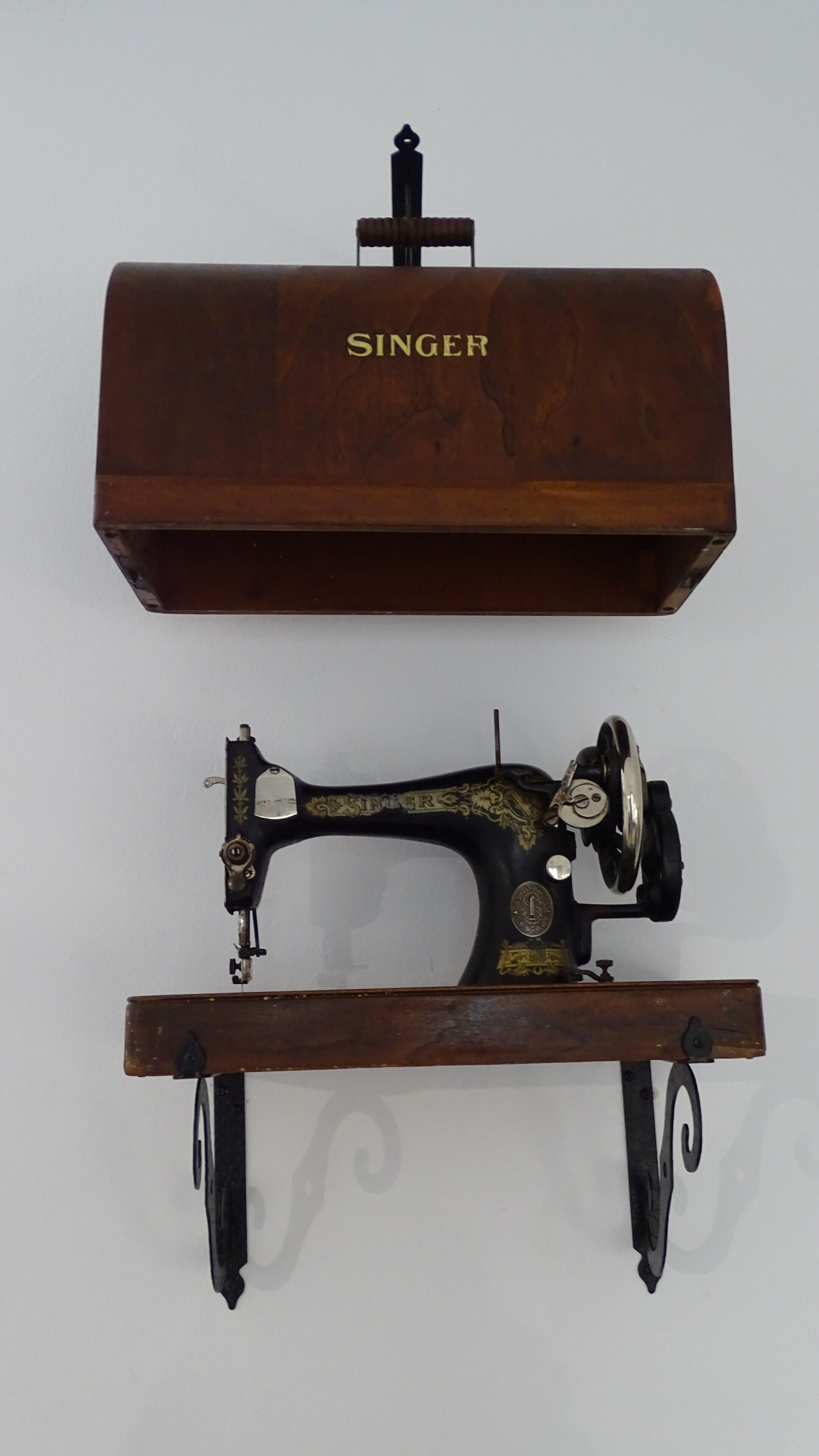 Una máquina de coser Singer sobre un atril de madera.