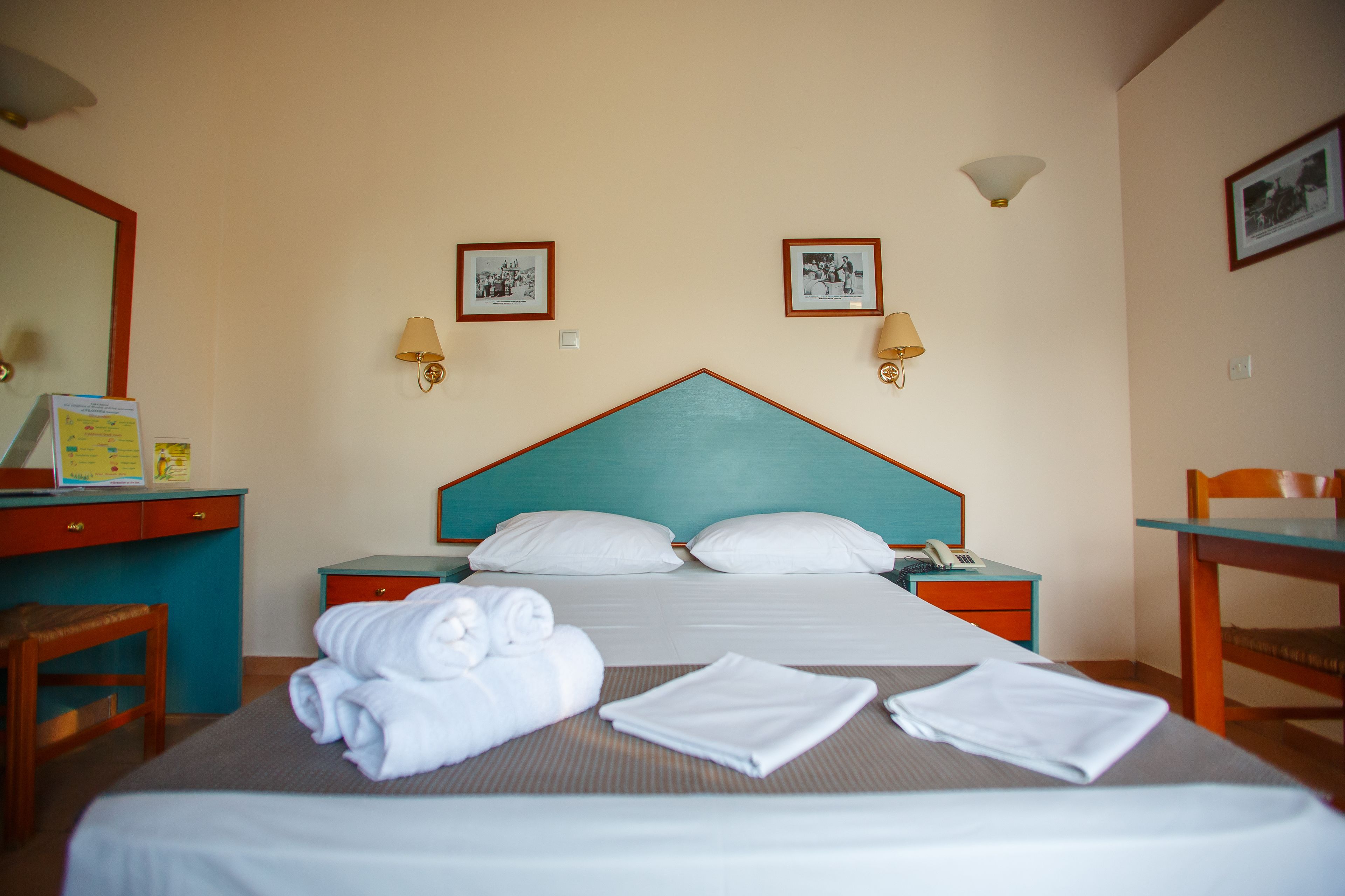 A hotel room with a bed, a desk, a chair, and a mirror.