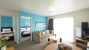 A modern hotel room with a bed, a sofa, a TV, and a dining area. - Fyffe On Riccarton (Christchurch)