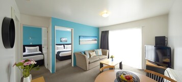 Una habitación de hotel moderna con cama, sofá, televisor y zona de comedor.