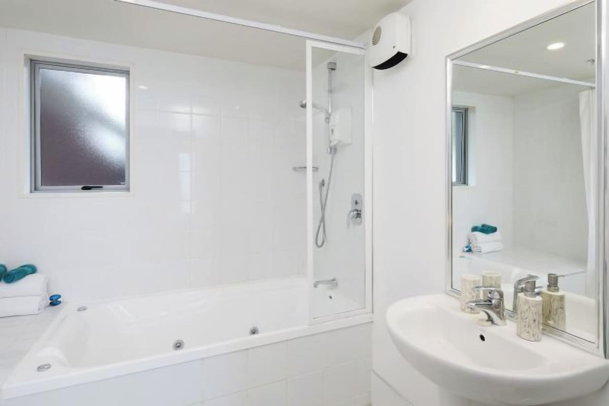 A modern bathroom with a glass-enclosed shower, a standalone bathtub, and a sink with a mirror.