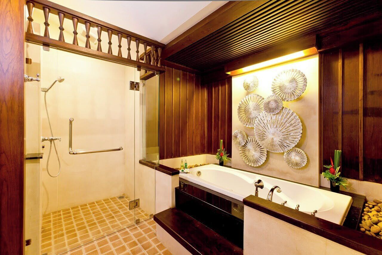 A modern bathroom with a glass shower enclosure, a freestanding bathtub, and a large mirror with decorative wall art.