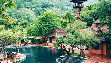 A resort with a swimming pool, a tower, and lush greenery.