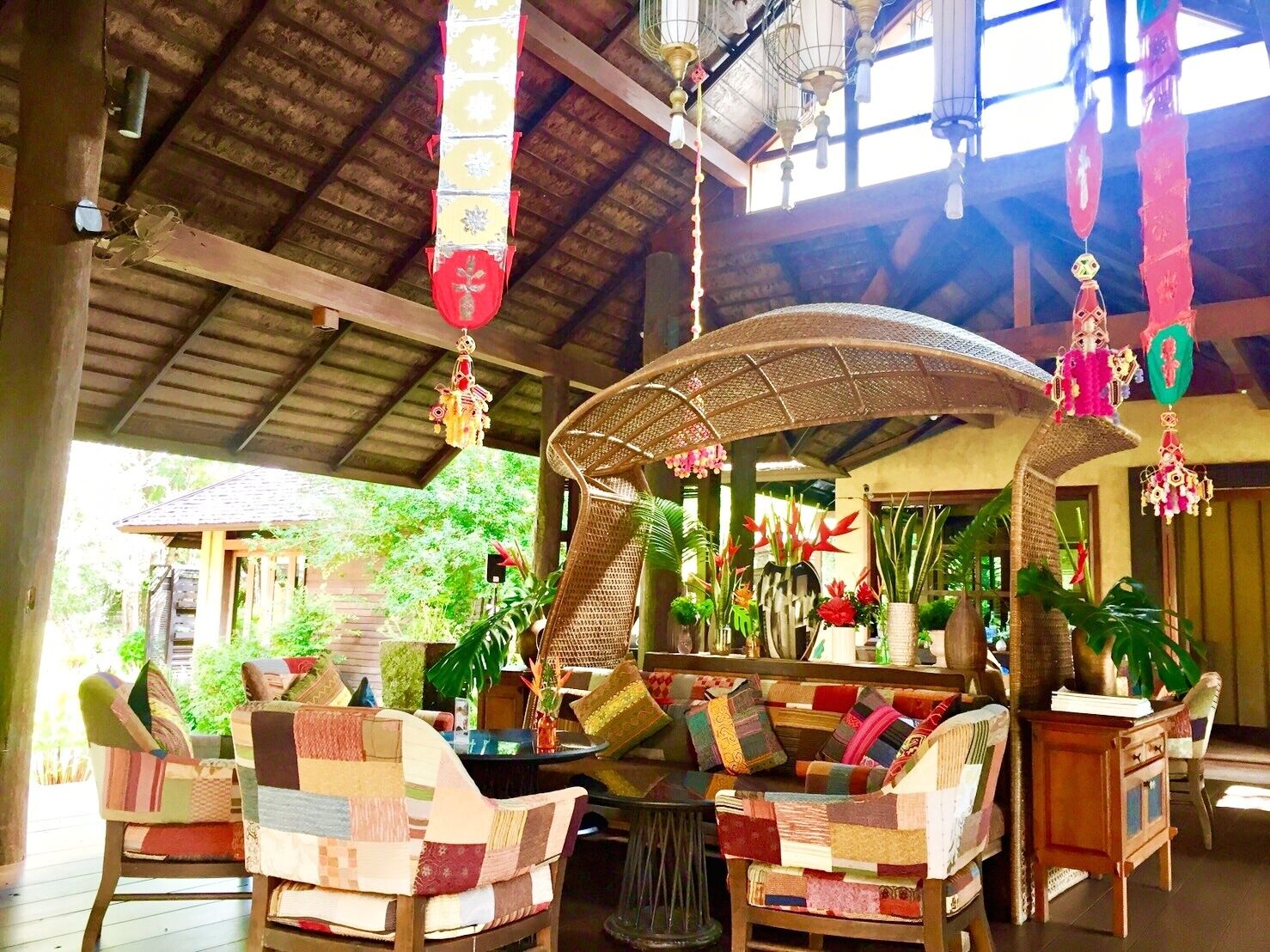 A covered seating area with wicker furniture and hanging decorations.