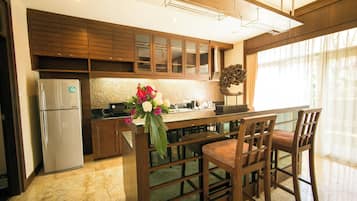 A modern kitchen with wooden cabinets, a marble countertop, and a built-in island with bar stools.
