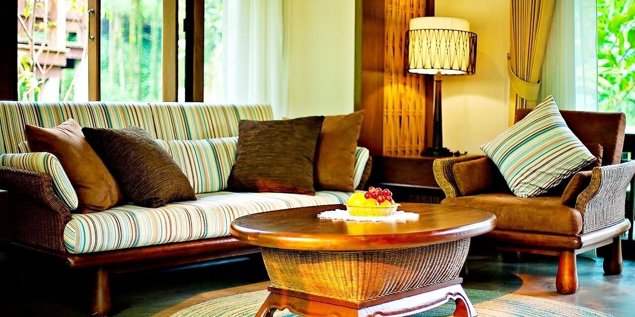 A cozy living room with a striped sofa, a round coffee table with fruit, and a lamp.