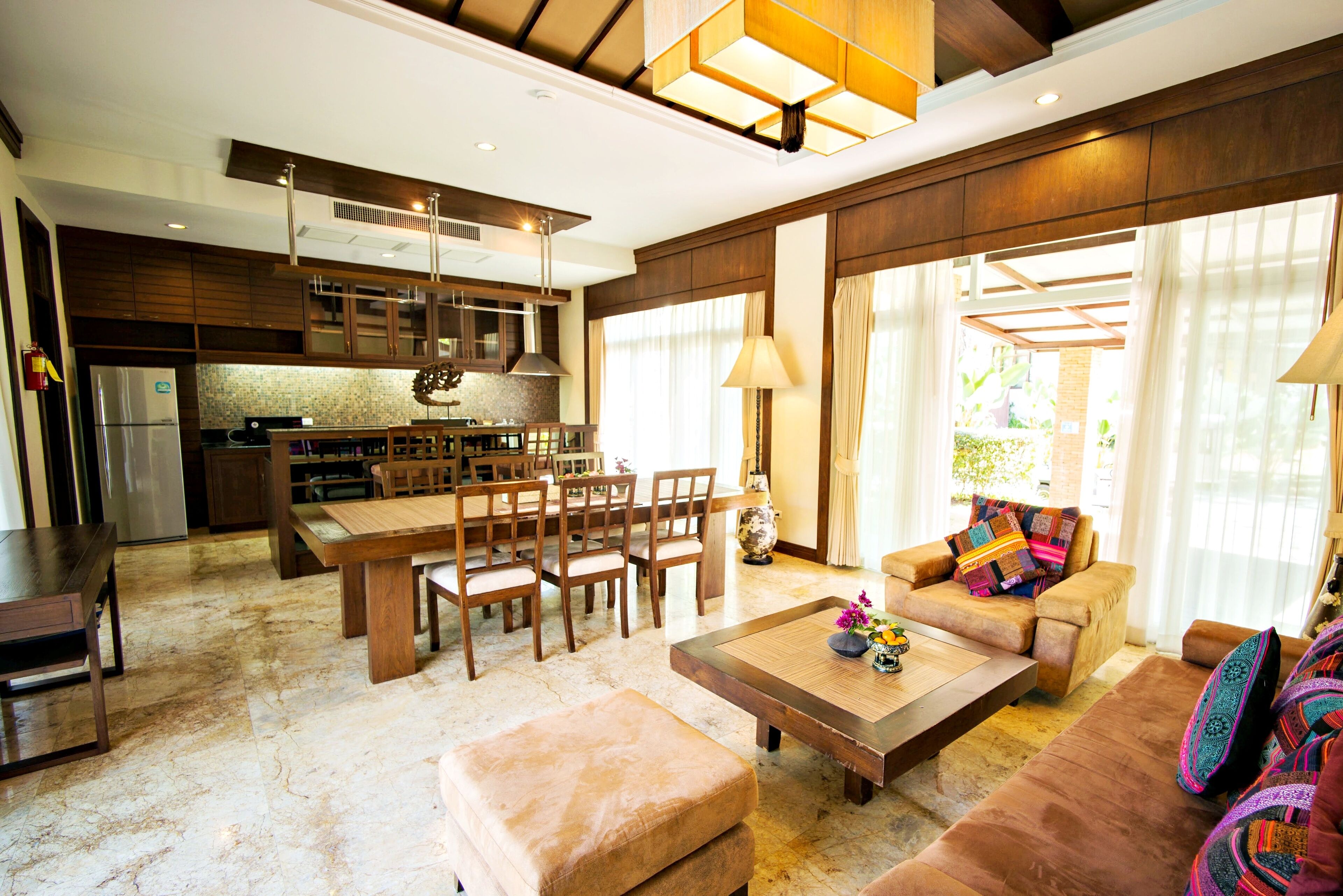 A spacious living area with a large wooden dining table, comfortable seating, and a kitchen in the background.