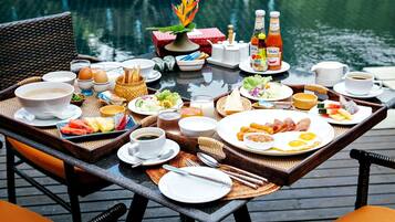 A breakfast table set on a wooden deck with a view of a body of water.
