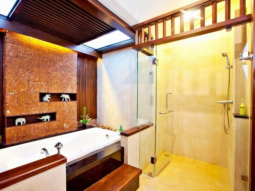 Une salle de bain moderne avec un mur en pierre, une baignoire, une cabine de douche en verre et des éléments décoratifs en bois.