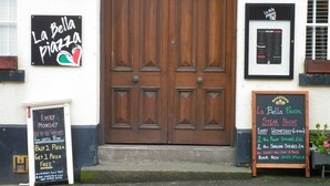 A restaurant with a wooden double door, signs advertising special offers, and a menu board. - Dixie Arms (Nuneaton)
