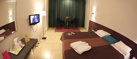 Une chambre d’hôtel comprenant un lit, un bureau avec des articles de toilette, une télévision et une vue sur la pièce.