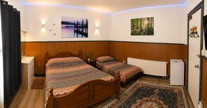 A bedroom with two beds, a nightstand, a radiator, and a small refrigerator. - Heavenly Nights Guest House (Sheffield)