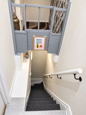 A staircase with a handrail, a 'MIND YOUR HEAD' safety sign, and a patterned carpet. - Heavenly Nights Guest House (Sheffield)