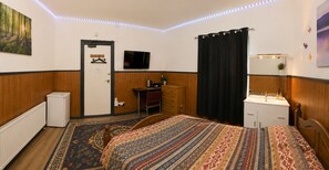 A hotel room with a bed, a desk, a television, a radiator, and a window with curtains. - Heavenly Nights Guest House (Sheffield)