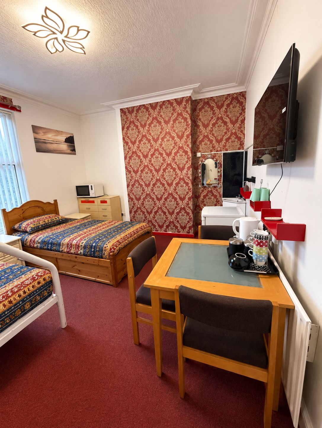 A hotel room with a bed, a desk with a chair, a television, and a window.