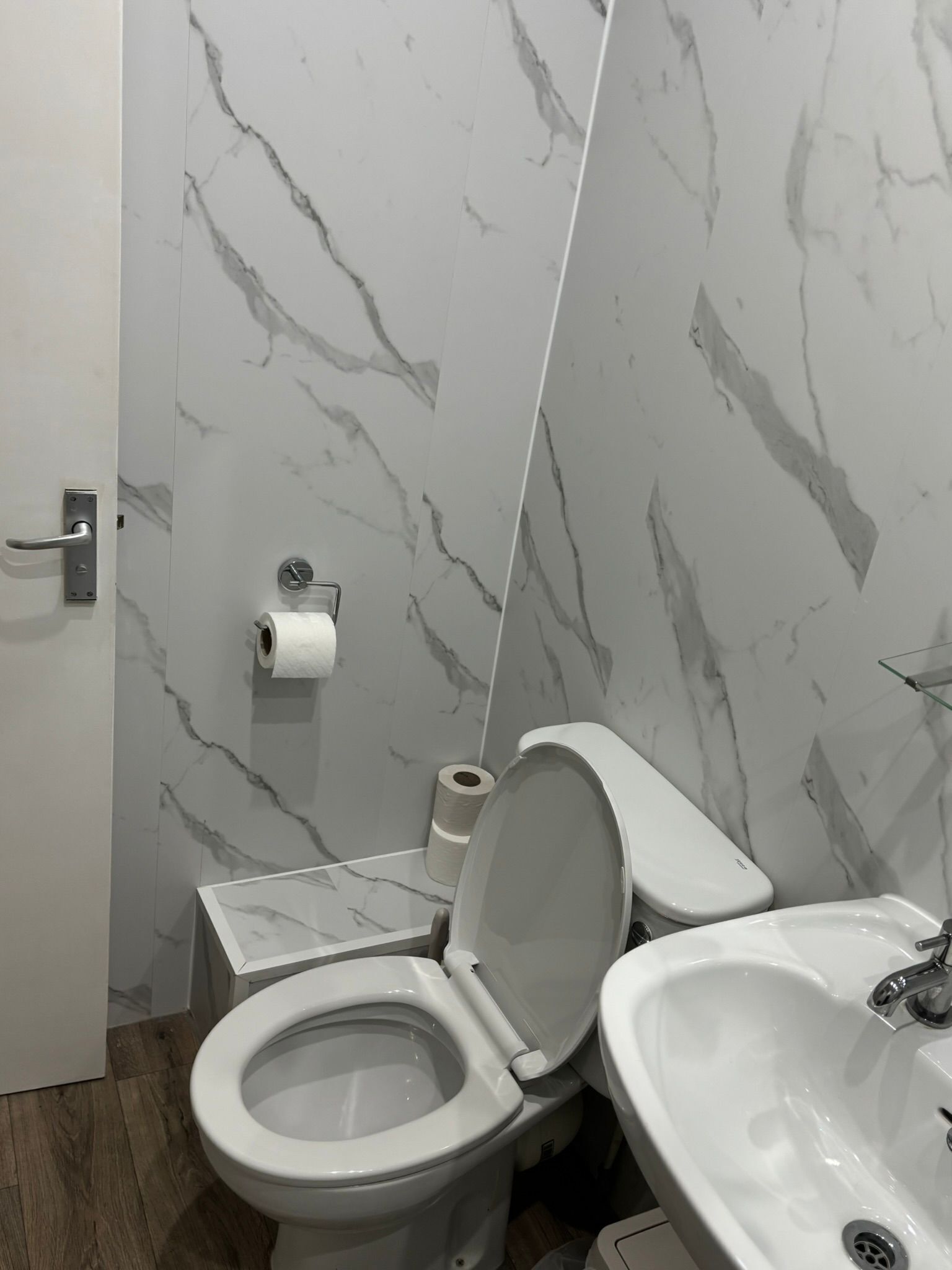 Un baño con inodoro, lavamanos y paredes de mármol.