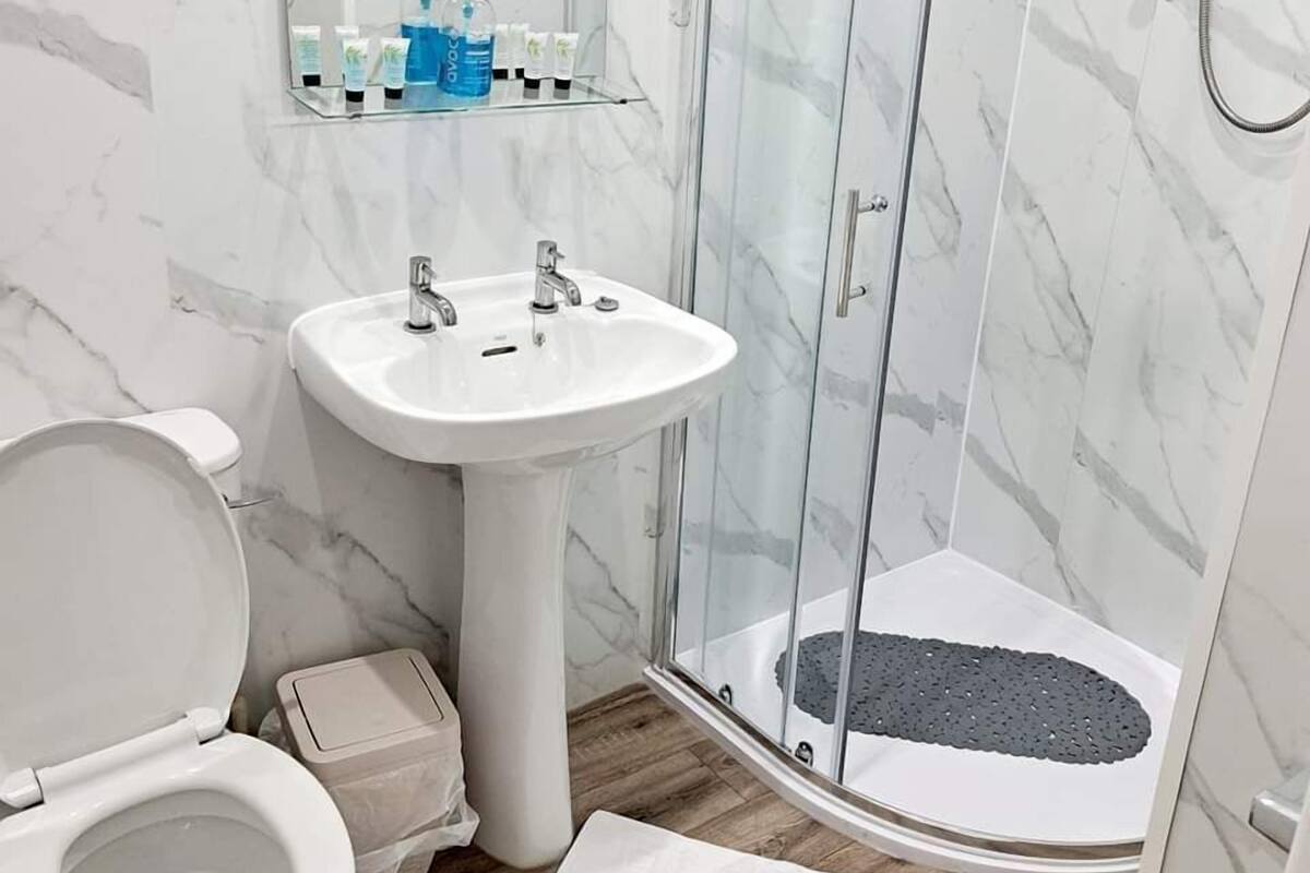 A bathroom with a white sink, a toilet, and a glass-enclosed shower area.