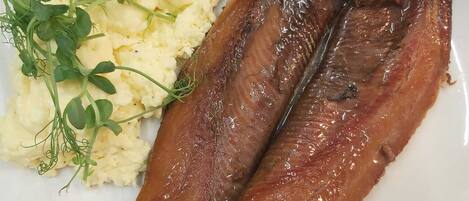 Ein Teller mit zwei gegrillten Fischen, Kartoffelpüree, einer gegrillten Tomate und etwas Salat.