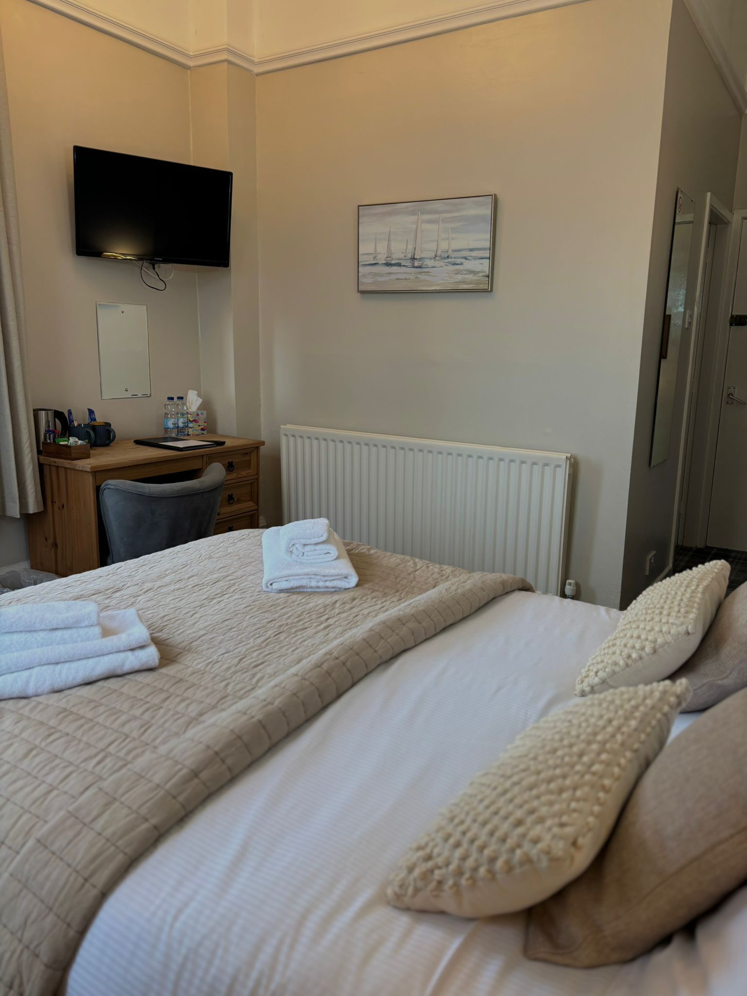 Una habitación de hotel con cama, escritorio, silla, televisor y un cuadro en la pared.