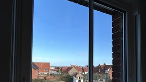 Ein Fenster mit Blick auf eine Wohngegend, inklusive Häuser und einer kleinen Konstruktion mit einer Rutsche.