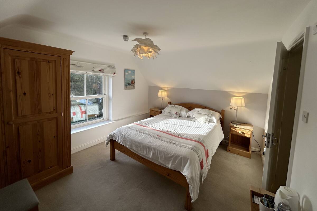 A bedroom with a wooden bed, bedside lamps, a window, and a wardrobe.