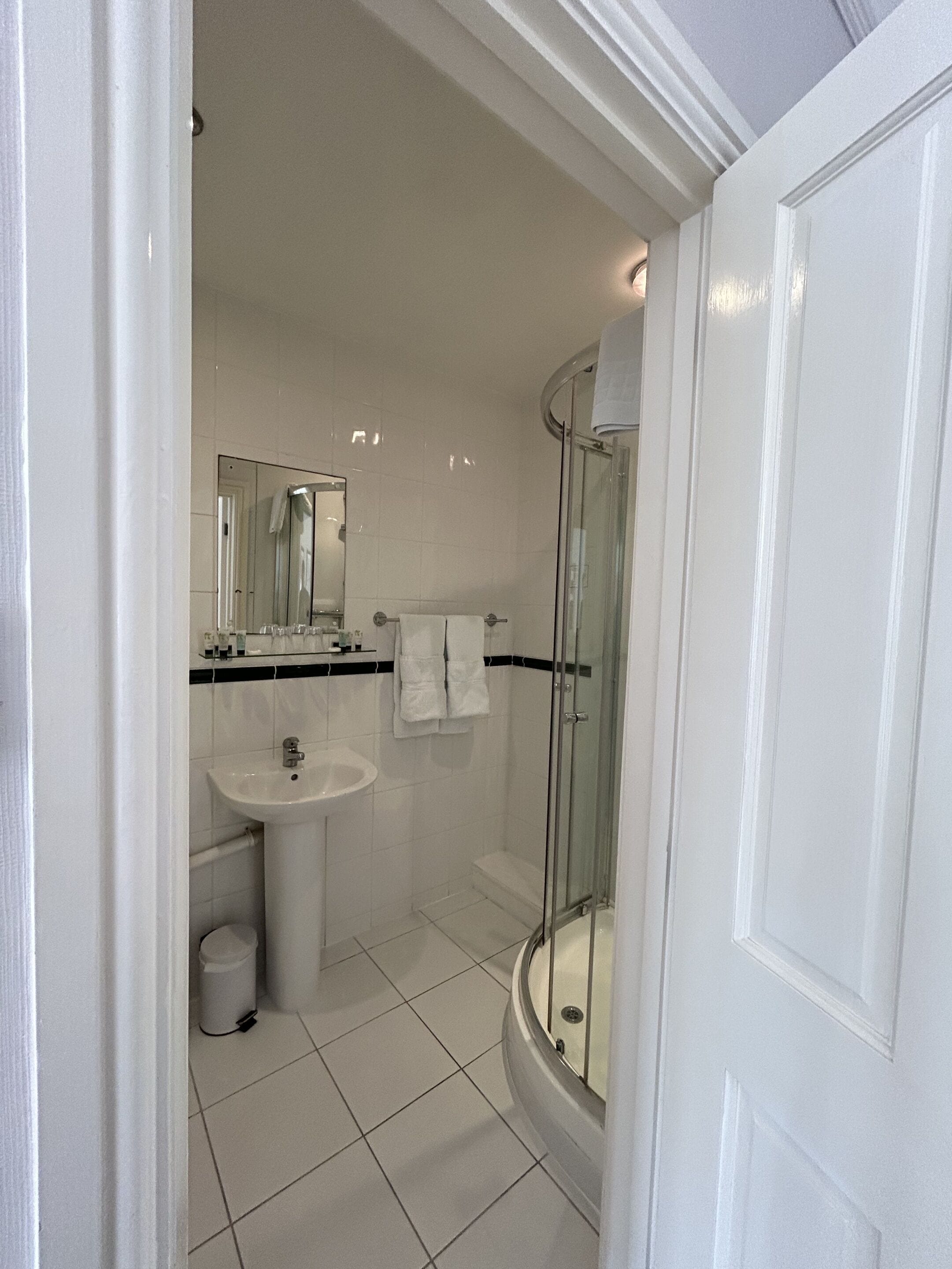 A bathroom with a sink, mirror, and glass-enclosed shower.