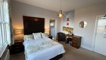 Un dormitorio con cama, lámparas de noche, escritorio, silla, un cuadro y un espejo en la pared.