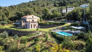 Uma villa com piscina, rodeada por vegetação exuberante e colinas.