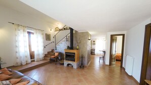 Uma sala de estar ampla, com lareira, escada e área de jantar.