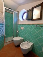 Un baño con ducha, dos inodoros y un bidé.