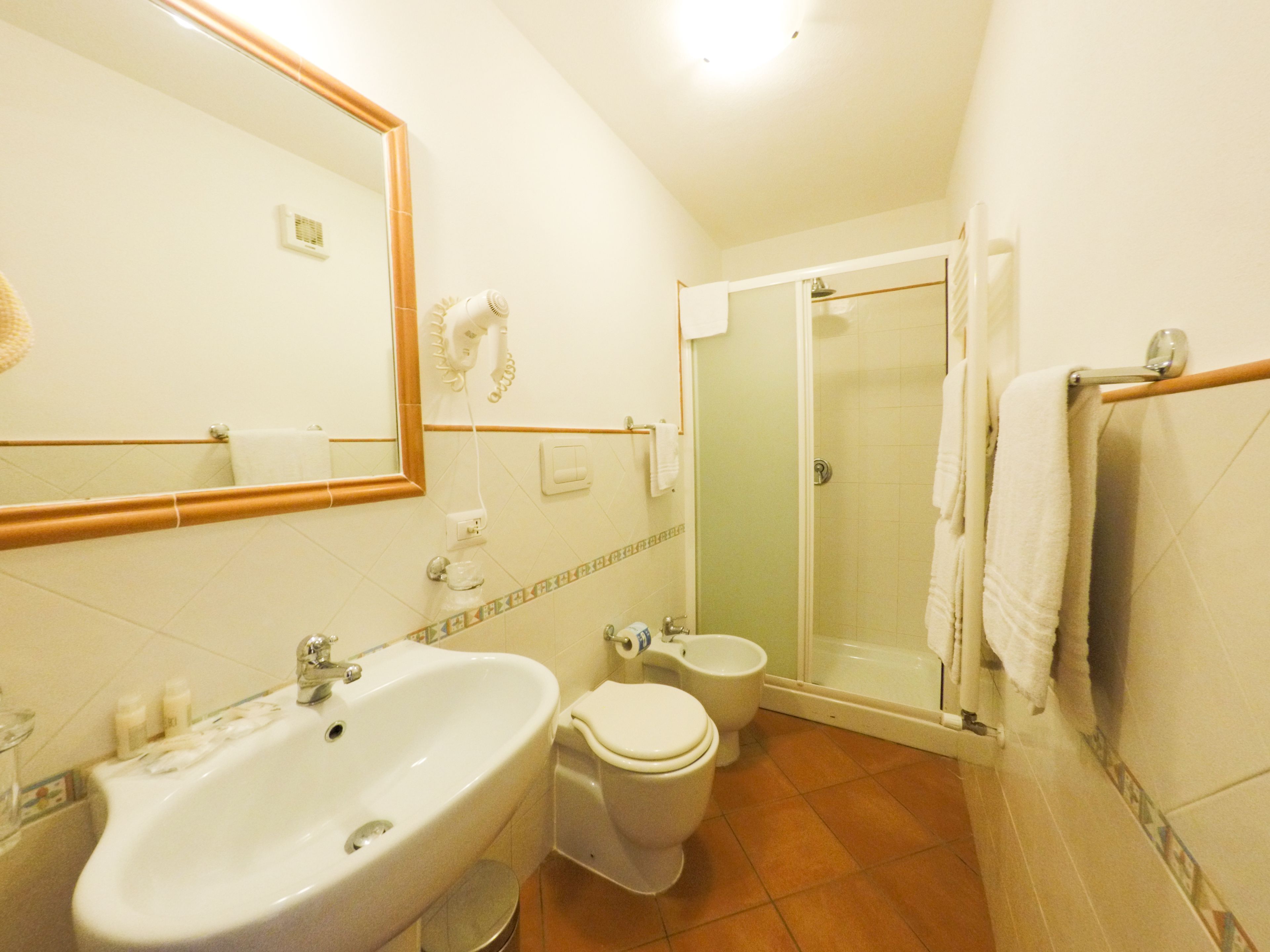 Ein Badezimmer mit Waschbecken, Toilette, Bidet und einer Duschkabine.