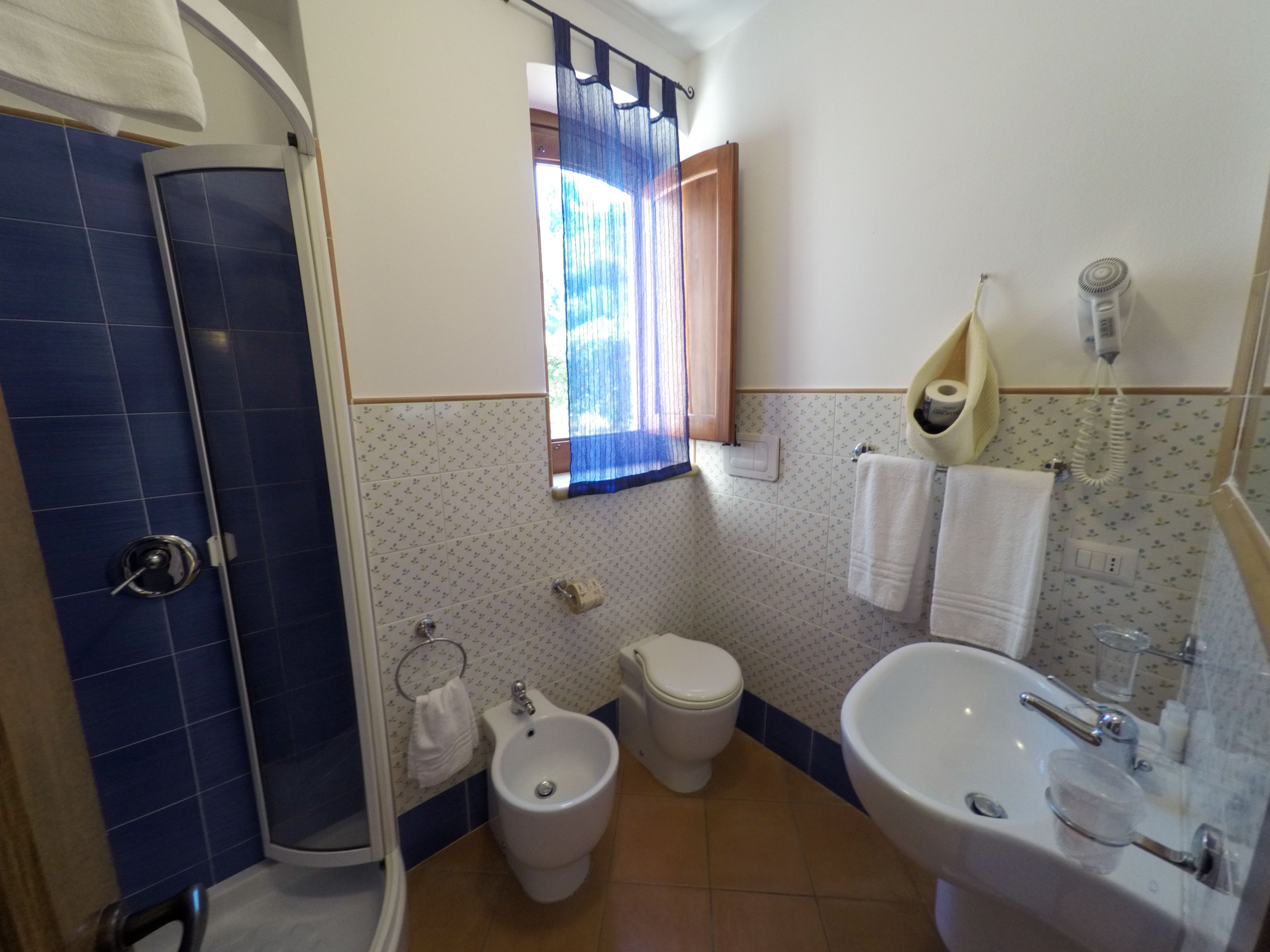 A bathroom with a shower, bidet, toilet, and sink.