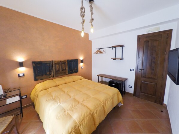 Un dormitorio con una cama grande, una puerta de madera, una mesita pequeña y luces fijadas en la pared.