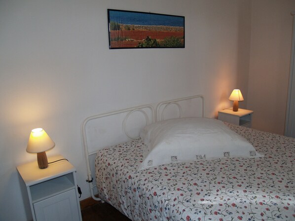 A single bed with a floral bedspread, two bedside tables with lamps, and a framed picture on the wall.