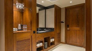 A modern bathroom with wooden cabinetry, a large mirror, a sink, and a towel rack. - The Swiss Residence (Kandy)