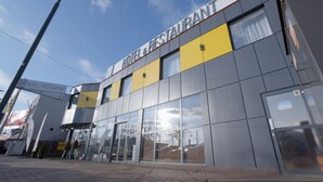 A modern building with a sign reading "HOTEL & RESTAURANT" and large glass windows. - Gordon Hotel (Warsaw)