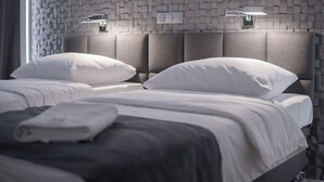A modern hotel room with two beds, grey headboards, and a textured wall. - Gordon Hotel (Warsaw)
