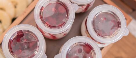 Una bandeja de vasos de plástico transparente llenos de un líquido rojo, posiblemente una bebida, y una bandeja de madera con asa.