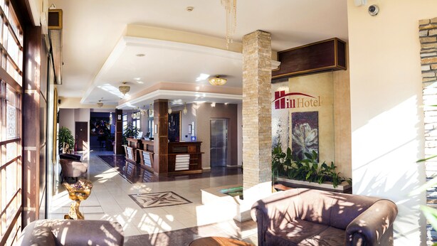 Un vestíbulo de hotel con mostrador de recepción, zona de estar y una escalera que conduce a los pisos superiores.