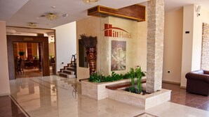 Un hall de hotel con una recepción, una escalera y una zona de estar.