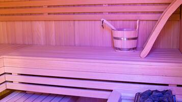 Un sauna avec des bancs en bois, un seau et un plateau de pierres.